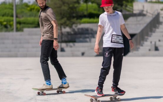 Two skateboarders are wearing their new men’s skate shirts.