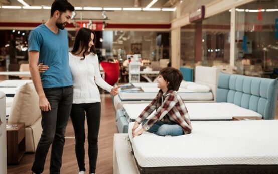 Family of 3 considering a Sealy mattress at a furniture store.