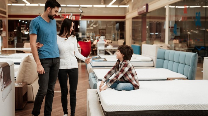 Family of 3 considering a Sealy mattress at a furniture store.